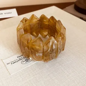 Close-up of amber marbled resin geometric bangle showing unique faceted texture