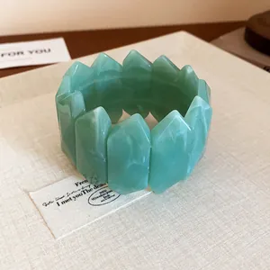 Close-up detail of green marbled acrylic bracelet featuring a unique faceted geometric design