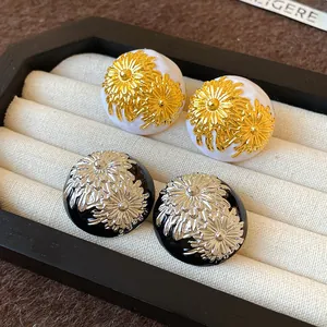 Detalle de pendientes de botón vintage de esmalte con margaritas en blanco y negro