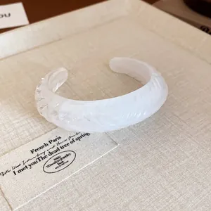 Detail shot of a minimalist white textured resin oval open cuff bracelet for women
