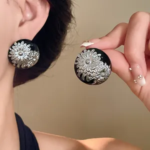 Primer plano de pendientes retro negros con diseño de flores plateadas