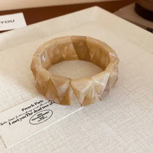 Close-up macro view of geometric faceted marbled resin bangle in cream and tan tones