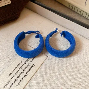 Elegant Klein blue flocked hoop earrings with silver needles on a textured jewelry tray