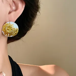 Primer plano de pendientes de botón florales vintage con esmalte blanco y detalles oro