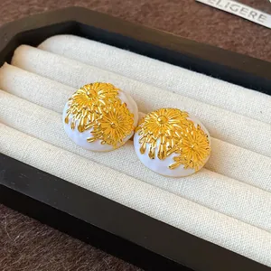 Primer plano de elegantes pendientes retro de esmalte con crisantemos dorados