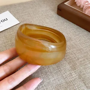 Vue détaillée d'un large bracelet en résine ambrée translucide à texture marbrée.
