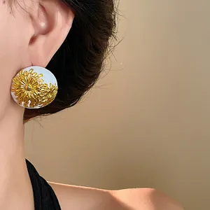 Vista detallada de pendientes vintage con flores esmaltadas puestos en la oreja
