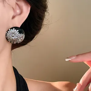 Primer plano de pendientes vintage de esmalte negro con flores plateadas en la oreja