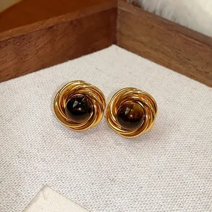 Dettaglio macro di orecchini a lobo vintage placcati in oro con pietra occhio di tigre