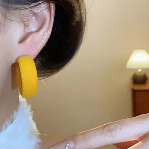 Detailed macro view of yellow flocked hoop earrings worn on ear with silver needle