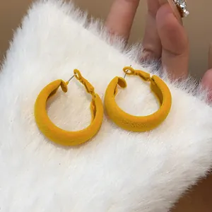 Detailed view of yellow flocked hoop earrings with a soft velvet texture finish