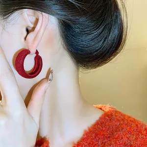 Detailed view of large red flocked hoop earrings worn by an elegant Asian model