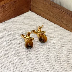 Primo piano di eleganti orecchini a lobo in occhio di tigre dorati dall'estetica vintage