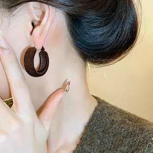 Detailed macro view of brown flocked hoop earrings for women, showcasing winter fashion texture.