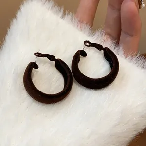 Close-up of brown flocked velvet hoop earrings with silver pins for autumn/winter.