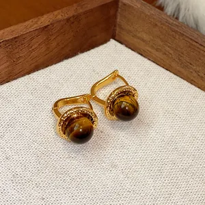 Dettaglio di orecchini vintage placcati oro con pietre occhio di tigre tonde lucide
