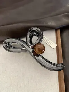 Detailed view of a sleek metallic hair claw clip featuring a brown amber-style bead.
