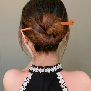 Detailed view of an elegant peach wood hair stick in a traditional Chinese bun hairstyle.
