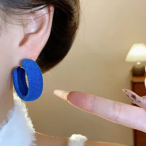 A detailed close-up showing the soft velvet texture of vibrant blue flocked hoop earrings