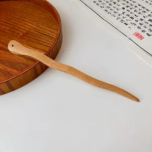 Detailed macro view of a wavy peach wood hairpin with a top hole for DIY accessories.