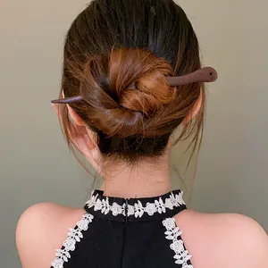 Detail view of a handmade peach wood hair stick styled in an elegant hair bun.