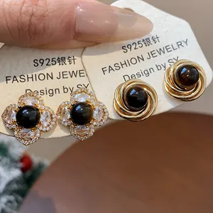 Dettaglio di orecchini vintage placcati oro con occhio di tigre e perni in argento S925
