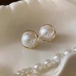 Elegant French style round pearl stud earrings with a polished gold rim finish