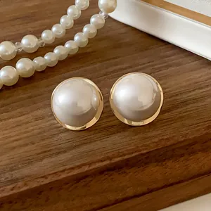 Close-up view of elegant French-style large pearl stud earrings with gold-tone base