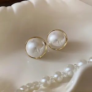 Detailed macro shot of vintage-style round pearl stud earrings with gold trim