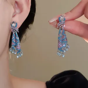 Close-up of ethnic style sparkling blue and pink crystal skirt dangle earrings.