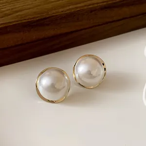 Close-up of elegant French vintage pearl stud earrings with gold metallic rim