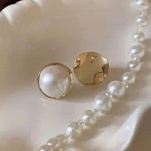 Close-up view of French retro pearl stud earrings with gold rim on a white plate