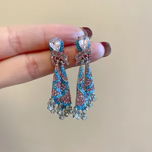 Detailed close-up of ethnic style skirt earrings with pink and blue crystals.