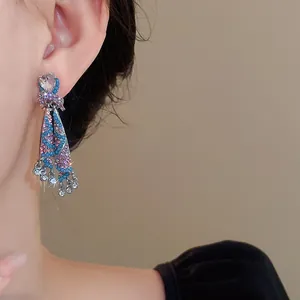 Close-up of sparkly ethnic skirt-shaped dangle earrings worn on a model's ear for detail