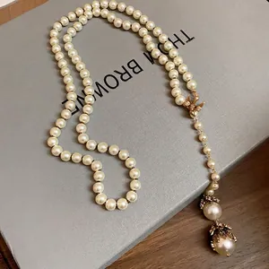 Elegant long baroque pearl necklace featuring a gold bird charm and crystal accents