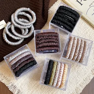 Close-up view of five-piece satin spring hair tie sets in clear acrylic gift boxes.
