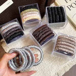 Close-up of silk-like fabric hair ties in clear storage box with hand-held detail
