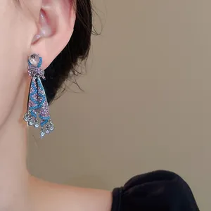 Exquisite close-up detail of ethnic style rhinestone skirt tassel earrings on model's ear