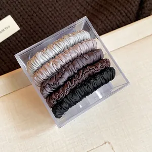 Detailed view of 5-pack neutral-toned ruched satin hair scrunchies in a clear box