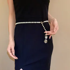 Close-up of elegant Baroque pearl waist chain featuring a sparkling bird charm and pearl drop