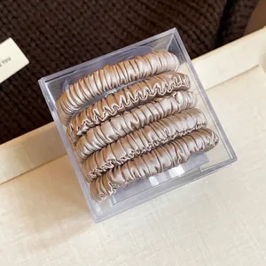 Close-up of 5-piece set of champagne fabric hair ties in a clear square box