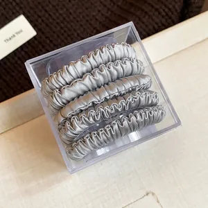 Detailed shot of a 5-piece silver fabric hair tie set in clear acrylic gift packaging.