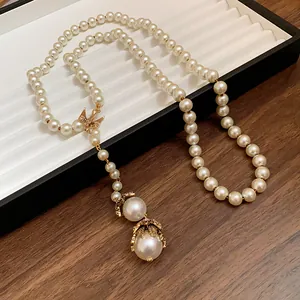 Detailed view of elegant baroque pearl necklace featuring a golden bird pendant and drops