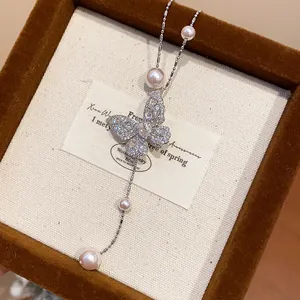 Detailed view of an elegant zircon butterfly necklace with pearls in a brown jewelry box