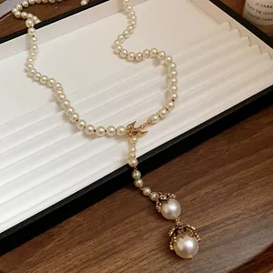 Close-up detail of vintage baroque pearl long necklace with golden bird charm and beads