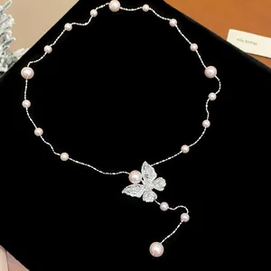 Detailed view of an elegant zircon butterfly pearl necklace on a black velvet background
