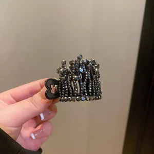Detail of crown-shaped hair claw clip decorated with sparkling black rhinestones