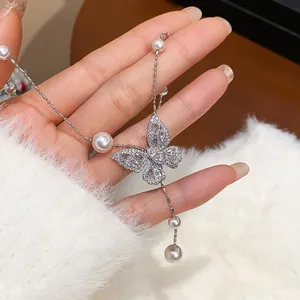Macro view showing zircon butterfly pendant with elegant pearl accents on silver chain