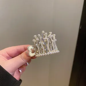 Detail view of a golden crown hair claw clip with elegant pearls and crystals.