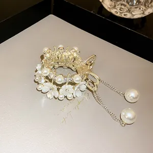 Close-up detail of a gold hair claw clip with floral pearl and tassel design for women
